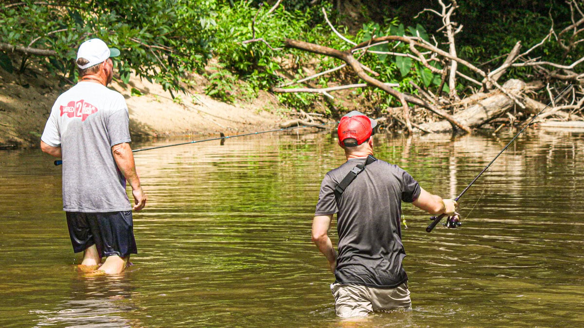 two fishermen wade fishing creek