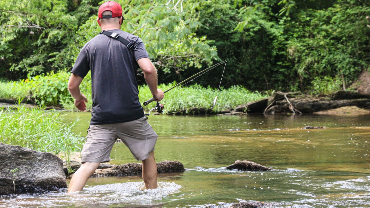 fisherman wading in creek