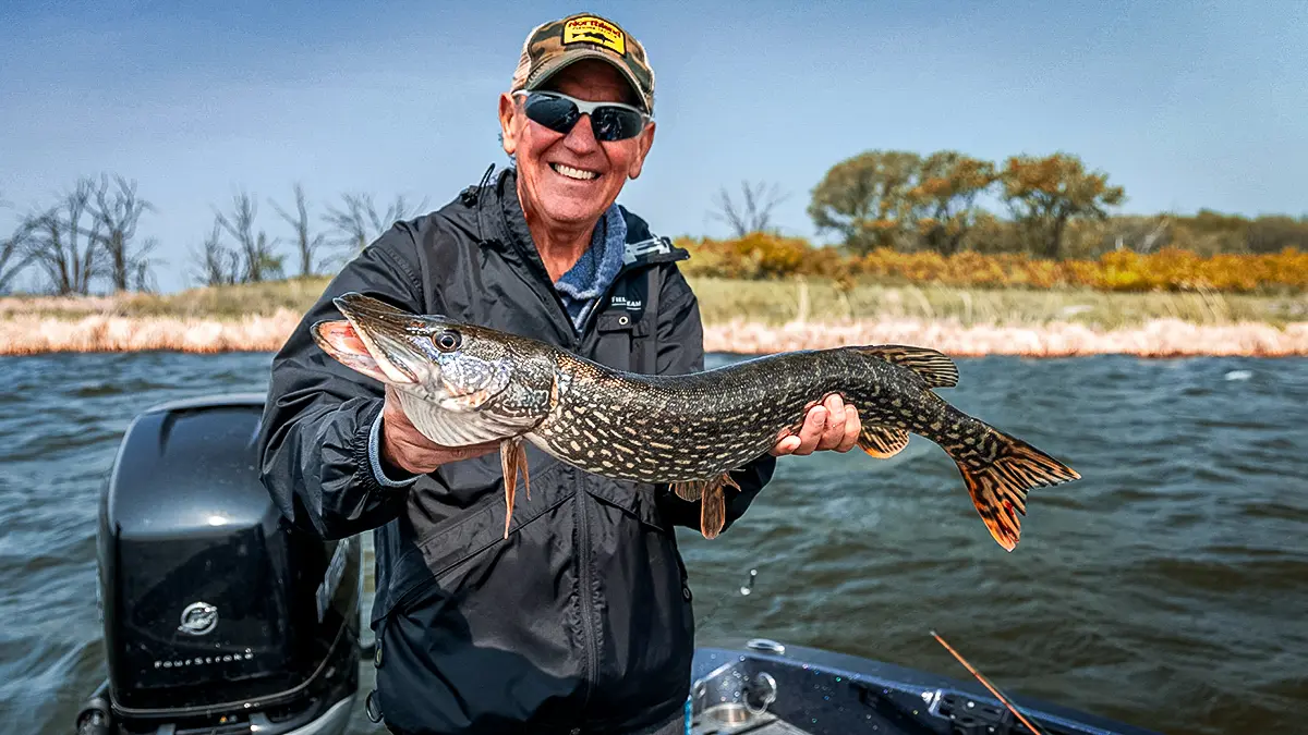older angler with a pike in a boat