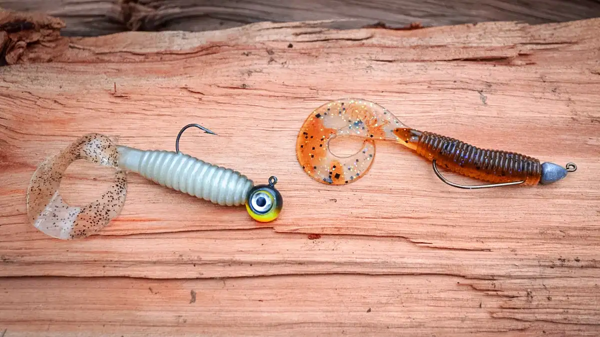 two curly tail grubs on a wood table