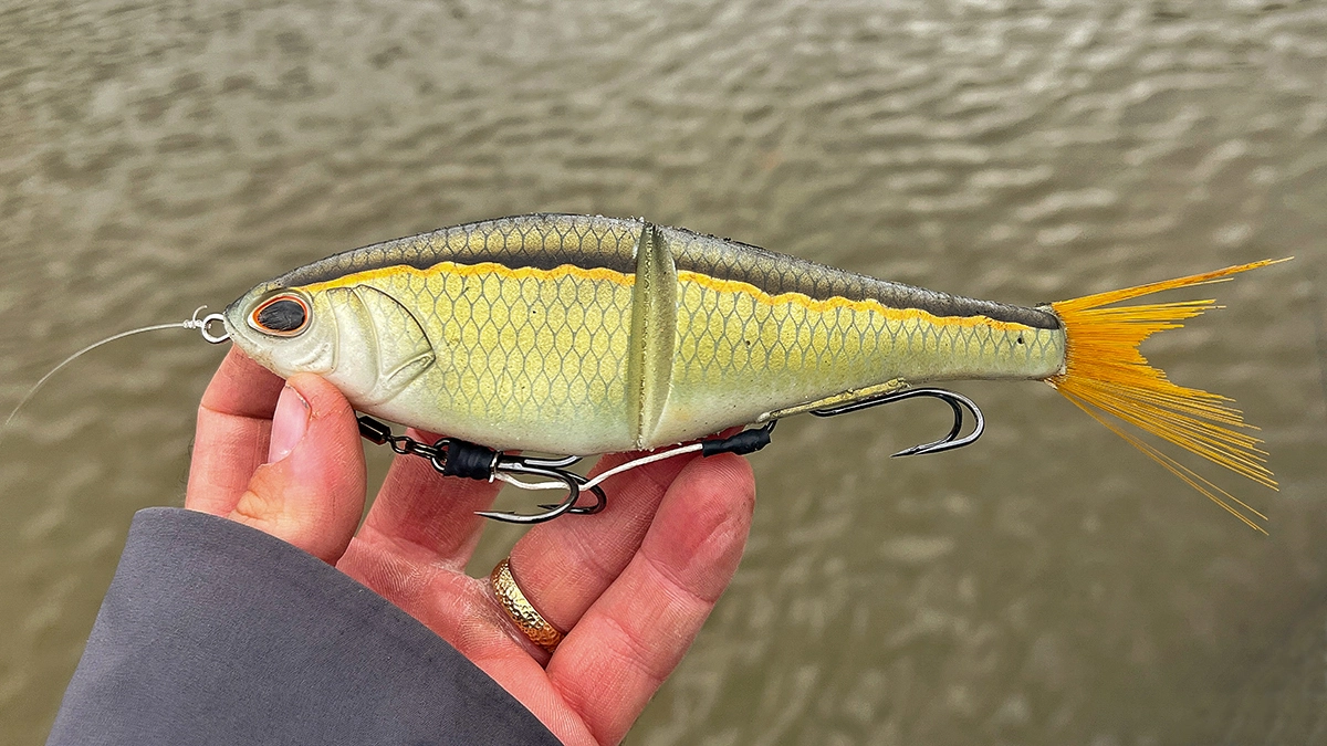 Hand holding a Berkley PowerBait Chop Block over the water