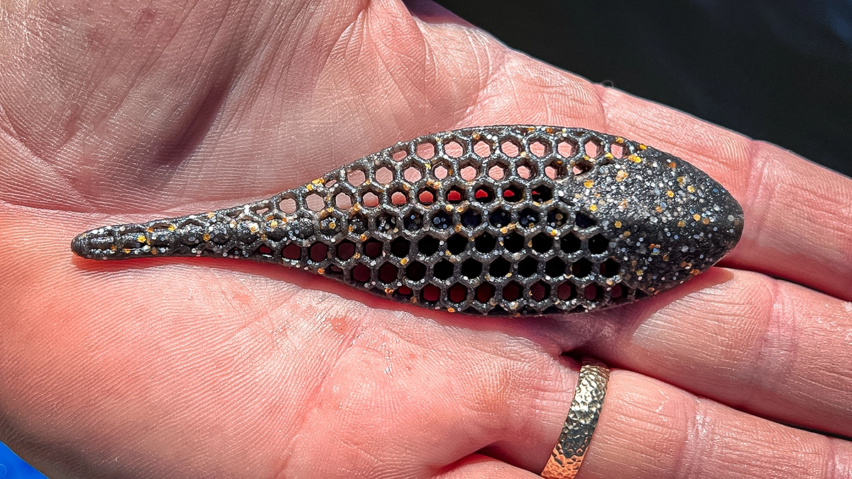 A closeup of a Berkley PowerBait Maxscent Flux Gill Creature Bait held in an open palm