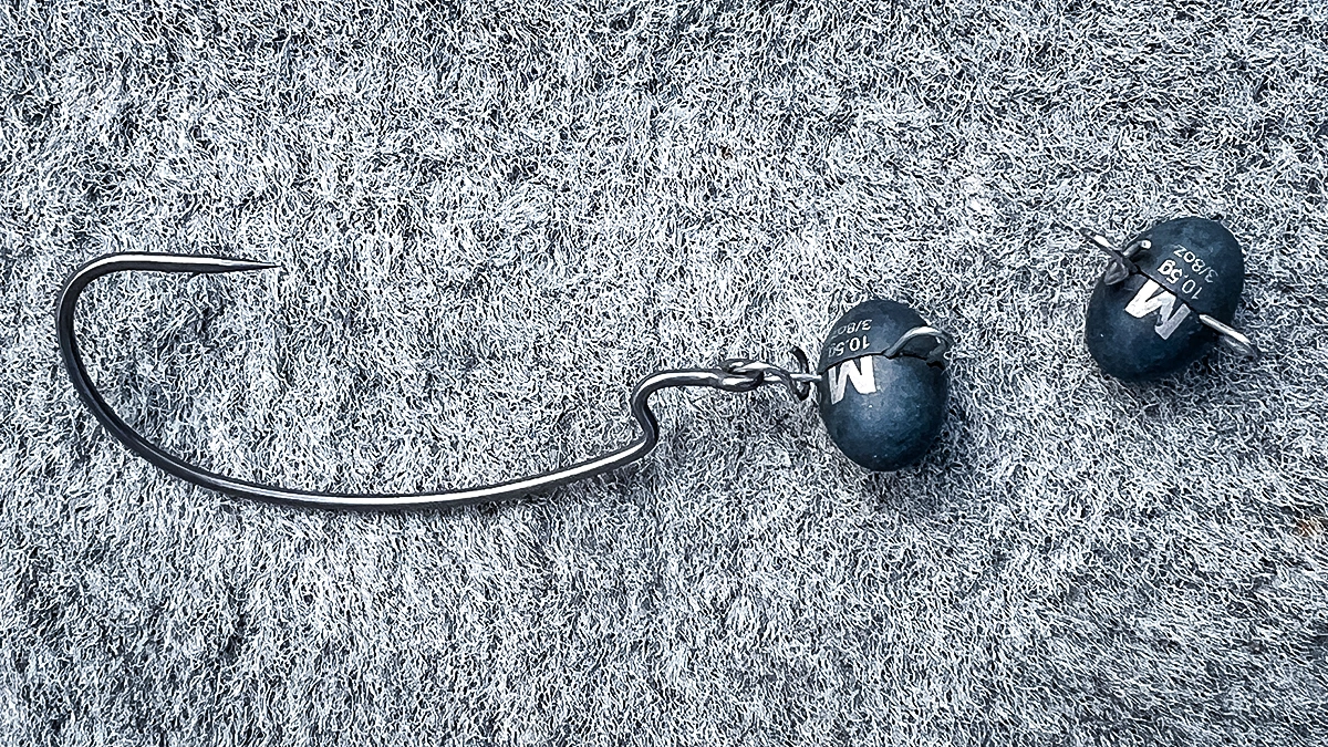 Two Mustad Tungsten TitanX Fastach Football Weights--one on a hook, one unattached--on the floor of a boat.