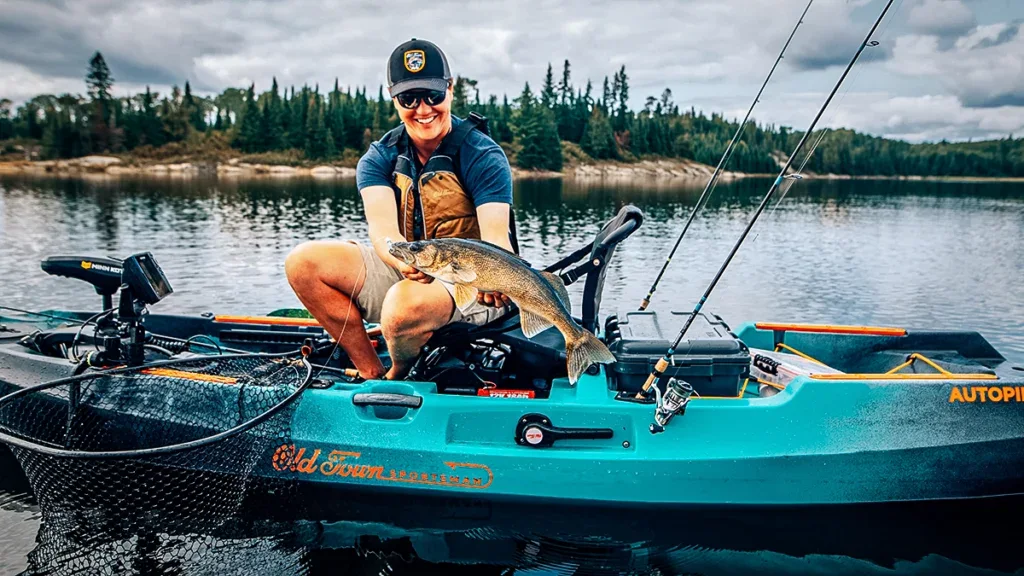 A woman catches a fish on a turquoise Old Town kayak
