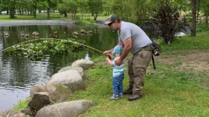 kid catching fish with help from dad