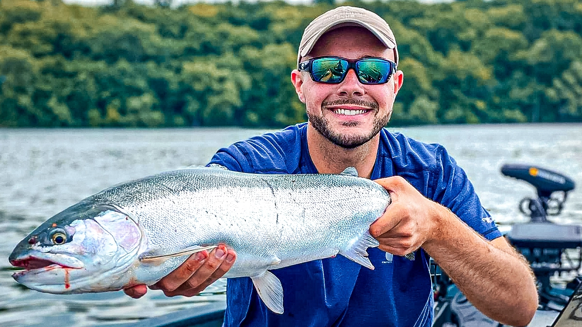 A man on a boat holds up a fish