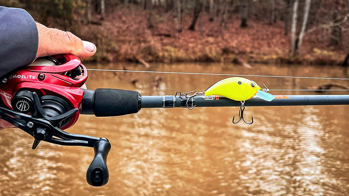 A rod held parallel to the water as a yellow bait is balanced on it