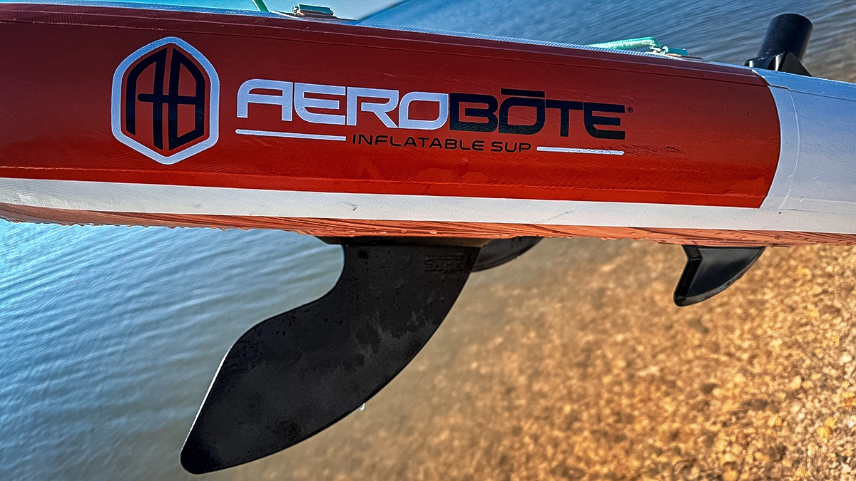 The side and fin of a BOTE HD Aero SUP, which is angled over the water
