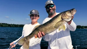 A man and a young angler show off a fish