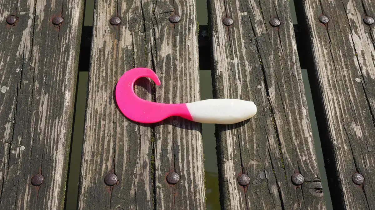 A pink and white Berkley Gulp! Minnow Grub lure on a dock