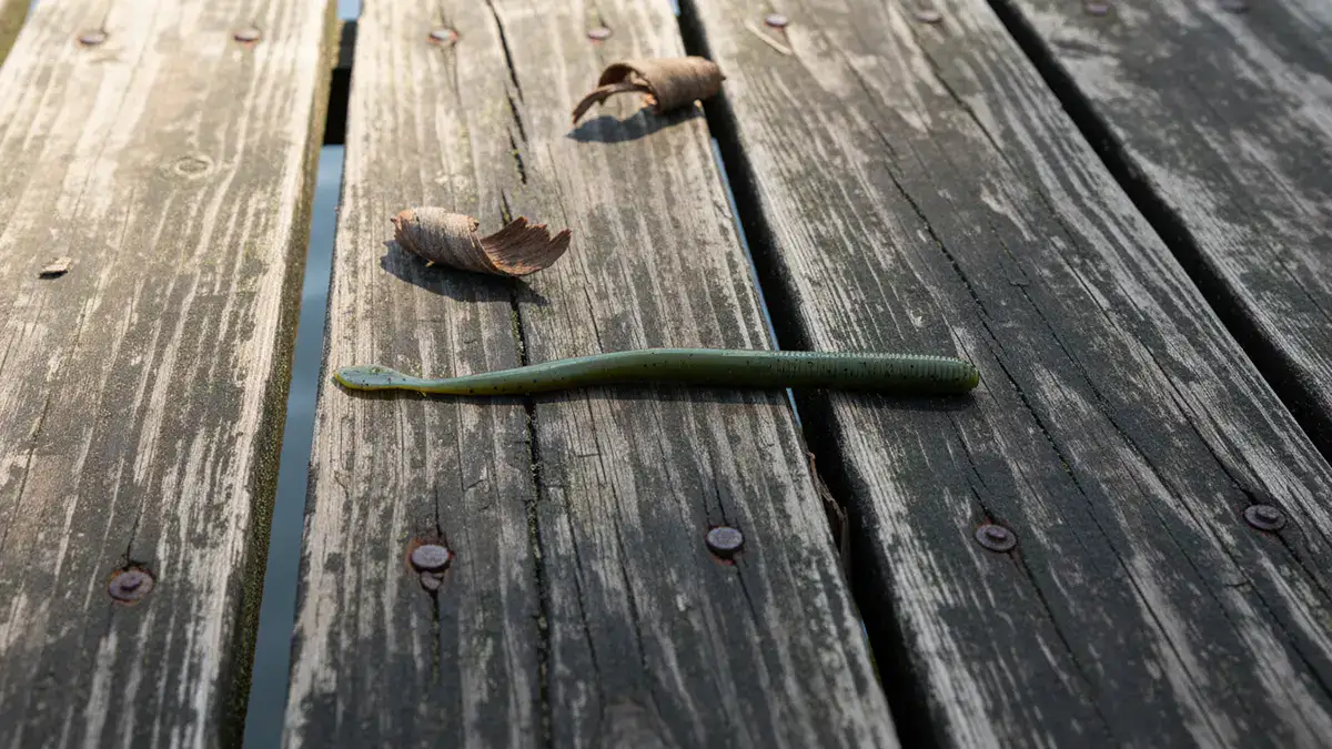 A green Berkley Gulp! Nightcrawler lure on a wooden dock