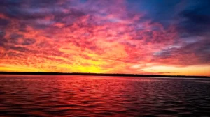 A vibrant yellow, orange, pink, and purple sky stretches above Lake Texoma.