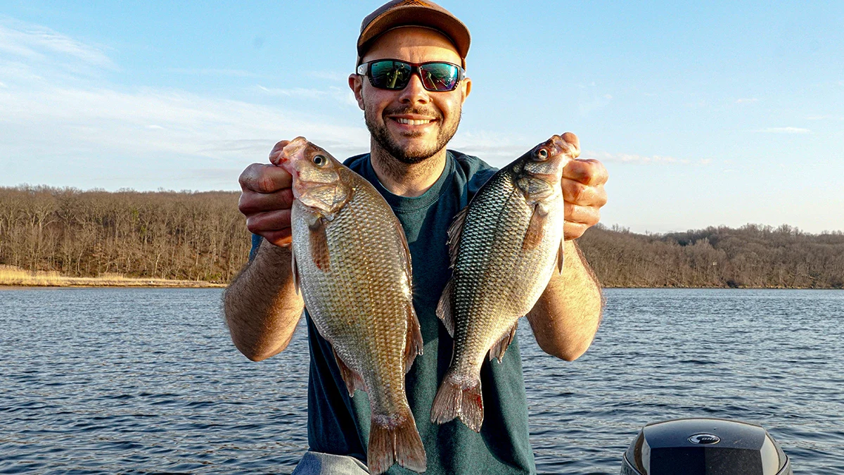 A man holds up two fish caught during the winter