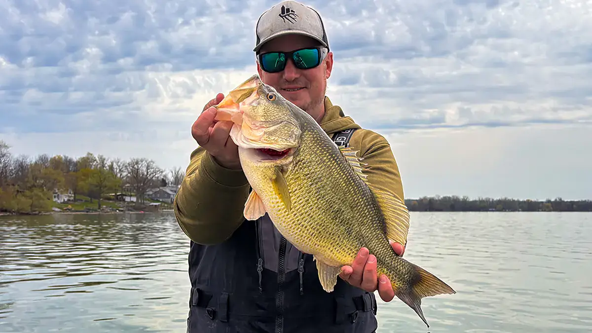 A man on the water holds up a bass