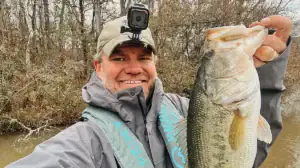 A man holds up a bass caught during the spawn.