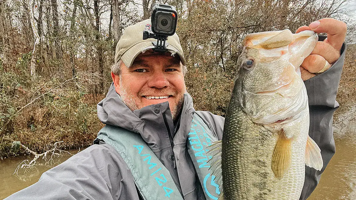 A man holds up a bass caught during the spawn.