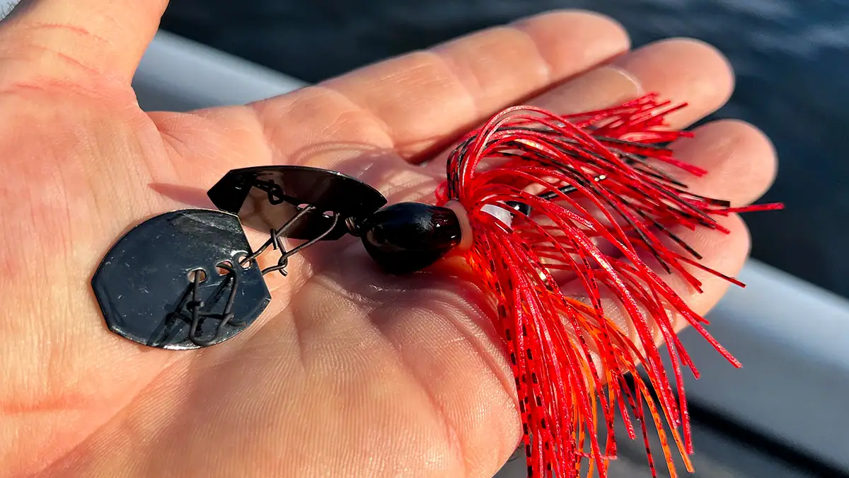 A hand holding an ABT Lures Original I-Vibe Bladed Jig in its open palm.