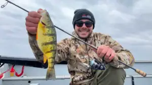 A man holds a Shimano Compre Lite Series rod and a panfish.