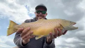A man holds up a brown trout caught in the springtime Great Lakes region.