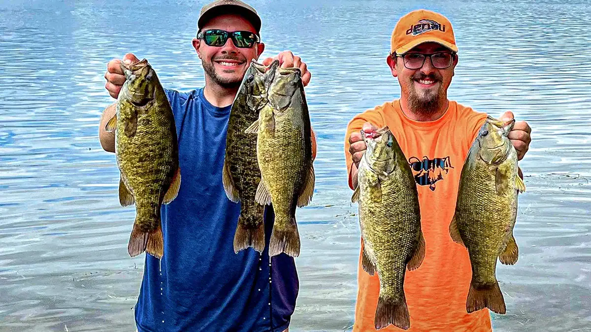 Two men on the water hold up five bass.