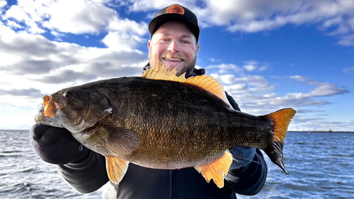 A man on the water holds up a bass caught during the ice-out period.
