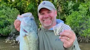 Fishing on a Budget lead image: a man, a bass, and the money you can save by sticking to a monthly fishing budget.