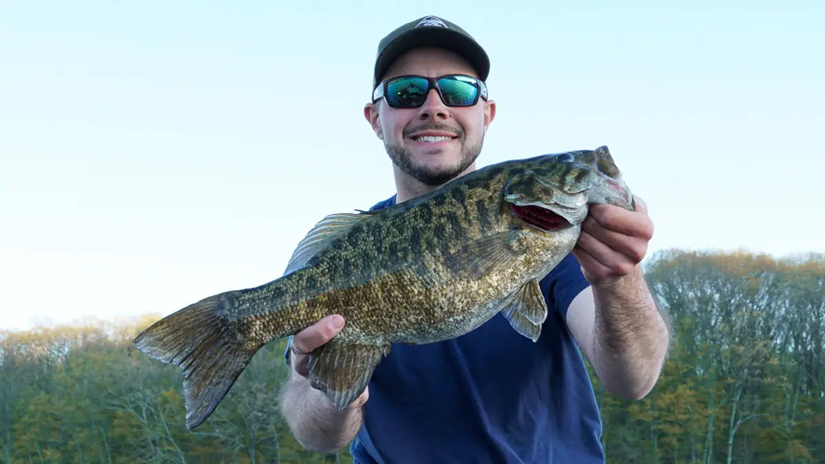 Man holding up a bass caught with one of the top five bait for post-spawn smallmouth success.