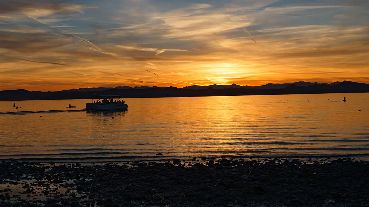 A boat and the scenery of Lake Havasu, Arizona, are washed in the golden-hour light of a sunset.