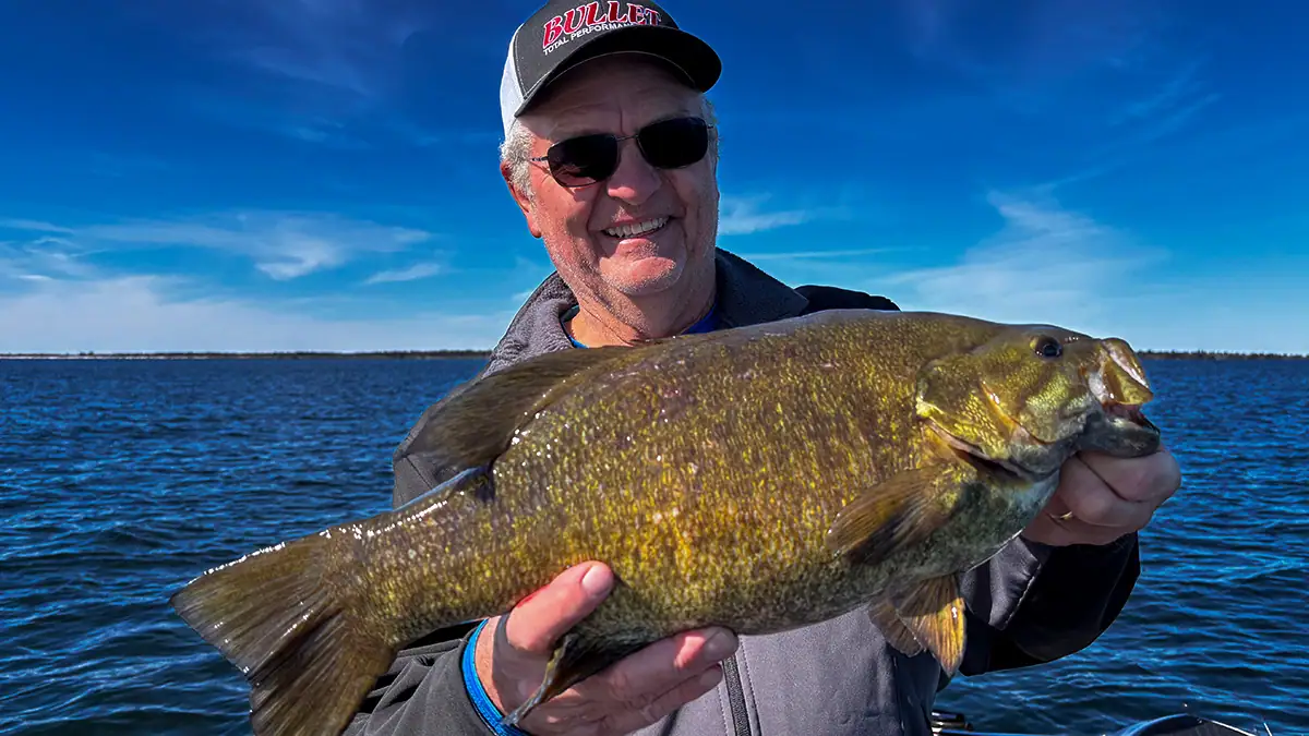 A man on the water holds up a bass.