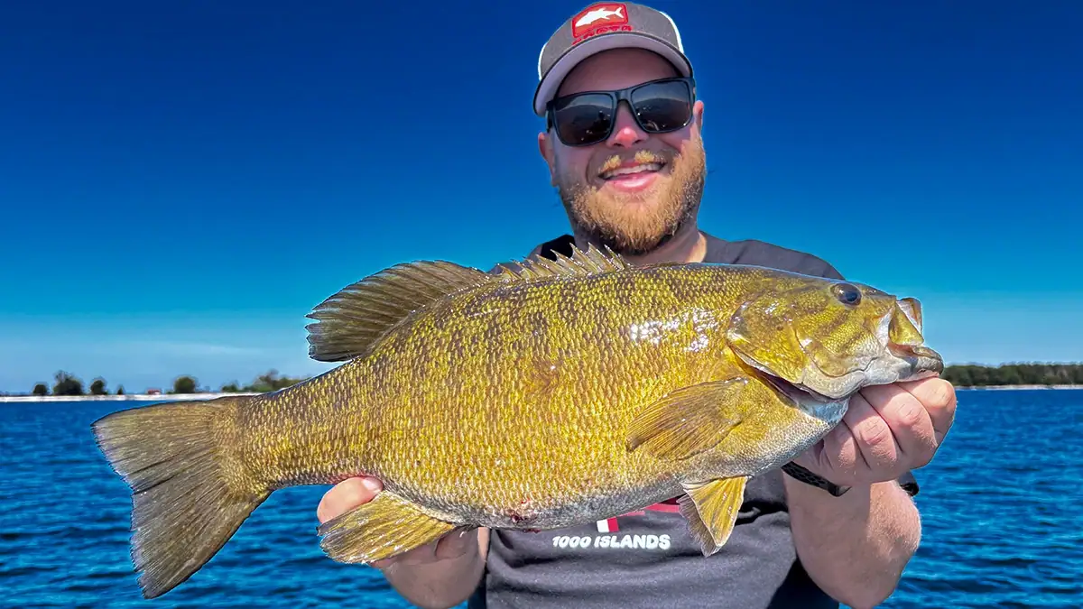 A man on the water shows off a bass.