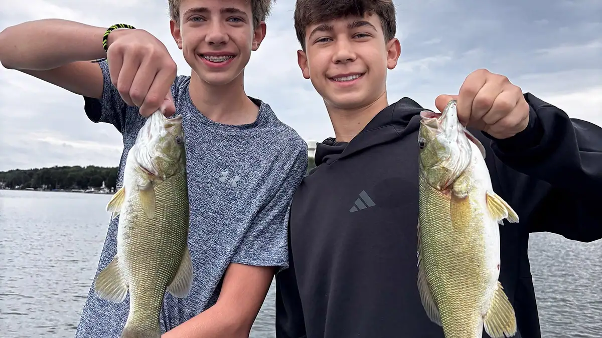 Two children hold the pond bass they caught.