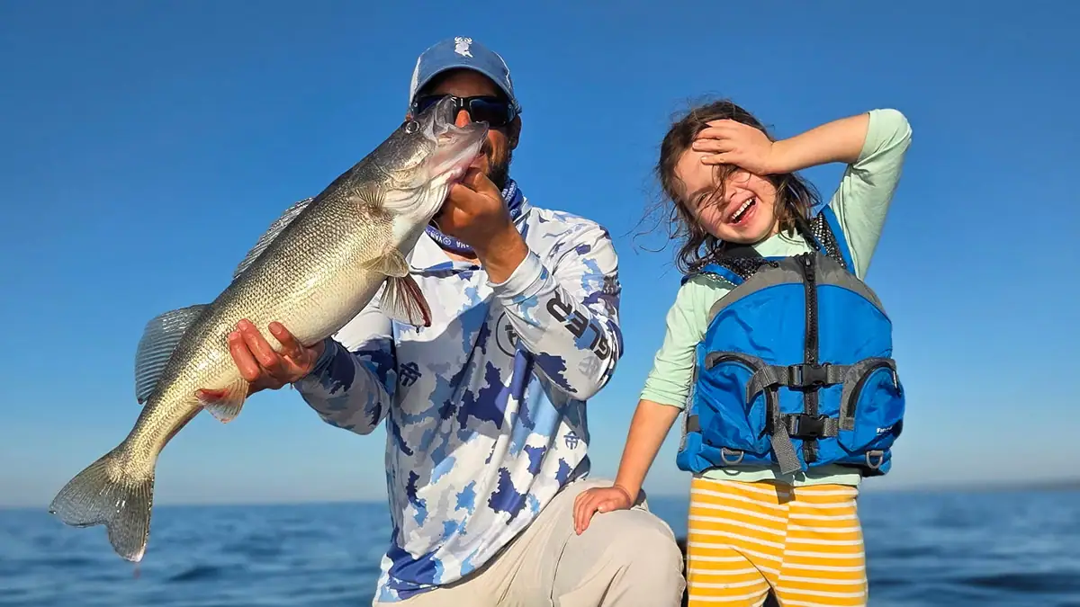 An angler and a child celebrate a great walleye catch.